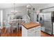 Bright kitchen showcasing stainless steel refrigerator, island with butcher block countertop and adjacent dining area with chandelier at 5426 Bobcat St, Frederick, CO 80504