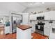 Well-lit kitchen with white cabinetry, stainless steel appliances, and a central butcher block island, offering modern convenience at 5426 Bobcat St, Frederick, CO 80504
