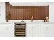 Modern basement bar with a wine fridge, gold faucet, and a stylish wood-paneled wall at 6325 W Portland Pl, Littleton, CO 80128