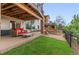Backyard patio with red couch, a spiral staircase, and a built-in stone fire pit with grass and garden area at 6614 W Gould Dr, Littleton, CO 80123