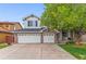 Two-story home with a brick front, three-car garage, and mature shade tree in the front yard at 6614 W Gould Dr, Littleton, CO 80123