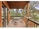 Covered wooden deck with glass-topped table offers beautiful views of the surrounding trees at 12191 Tecumseh Trl, Conifer, CO 80433