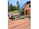 Beautiful cabin exterior with a wood deck and stunning landscaping and rock waterfall feature at 12191 Tecumseh Trl, Conifer, CO 80433