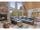 Bright living room with stone fireplace, wood ceiling, large windows, and an oversized leather sectional at 12191 Tecumseh Trl, Conifer, CO 80433