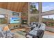 Cozy living room with a stone fireplace, wood ceiling, natural lighting, and comfortable leather seating at 12191 Tecumseh Trl, Conifer, CO 80433