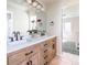 Bright bathroom featuring wood cabinets with double sink and view into adjoining bedroom at 5668 Red Fern Ct, Littleton, CO 80125
