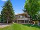 Back of house with a large wooden deck, surrounded by mature trees and a green lawn at 86 Woodland Cir, Highlands Ranch, CO 80126