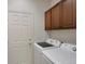Laundry room with washer and dryer, brown cabinets, and a white door at 86 Woodland Cir, Highlands Ranch, CO 80126