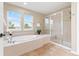Bright bathroom featuring a soaking tub under windows and a separate tiled glass shower at 3075 Greensborough Dr, Highlands Ranch, CO 80129