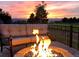 Inviting outdoor seating area with a stone fire pit and a beautiful sunset view of the mountains at 3075 Greensborough Dr, Highlands Ranch, CO 80129