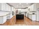 Spacious kitchen with white cabinets, granite countertops, hardwood floors and an island with black cabinets at 3075 Greensborough Dr, Highlands Ranch, CO 80129