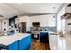 Bright kitchen featuring custom backsplash, stainless appliances, white cabinets, and a blue island with quartz countertops at 8463 Wheatgrass Cir, Parker, CO 80134