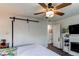Comfortable bedroom featuring a large barn door leading to a closet, a decorative fireplace, and a ceiling fan at 8463 Wheatgrass Cir, Parker, CO 80134