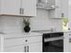 The kitchen features white cabinetry, modern appliances, white countertops, and a stylish tile backsplash at 2542 S Winona Ct, Denver, CO 80219