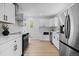 Modern kitchen with white cabinetry, stainless steel appliances, quartz countertops, and hardwood floors at 2542 S Winona Ct, Denver, CO 80219