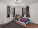 Bright bedroom with wood floors, two windows with gray curtains and a colorful quilt on the bed at 117 6Th St, Frederick, CO 80530