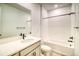 Well-lit bathroom featuring white subway tile, a shower-tub combo, and marble vanity at 8632 Hotchkiss St, Littleton, CO 80125