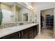 Bathroom featuring double vanity with mosaic tile backsplash, large mirror, and walk-in closet at 8272 E 55Th Pl, Denver, CO 80238