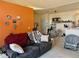 Cozy living room with a large couch, orange wall and view into the dining area at 14353 E 1St Dr # 302, Aurora, CO 80011