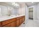 Bathroom featuring wood vanity, white countertops, double sinks, and walk-in closet at 9777 W Stanford Ave, Denver, CO 80123