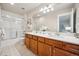 Bathroom with wood vanity, double sinks, white countertops, and shower/tub combo at 9777 W Stanford Ave, Denver, CO 80123