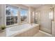 The bathroom features a soaking tub, tiled surround, large windows, and a walk-in shower with a gold frame at 22668 E Lake Pl, Centennial, CO 80015