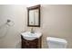 Compact bathroom with a dark wood vanity, framed mirror, and toilet, maximizing space and functionality at 22668 E Lake Pl, Centennial, CO 80015