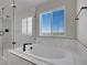Elegant bathroom featuring a soaking tub with marble surround and a glass enclosed shower next to a bright window at 6880 S Yantley Ct, Aurora, CO 80016