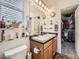 Dual sink bathroom featuring a window for light, an adjacent closet, and lots of storage space at 17950 E 54Th Ave, Denver, CO 80249