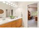 Bright bathroom featuring a double sink vanity with wooden cabinets and a large mirror reflecting into an adjacent room at 30205 Telluride Ln, Evergreen, CO 80439