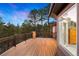 Exterior view of a spacious wooden deck at dusk with views of the surrounding pine trees at 30205 Telluride Ln, Evergreen, CO 80439