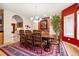 Elegant dining room with a large wooden table, red accent wall, decorative rug and modern chandelier at 30205 Telluride Ln, Evergreen, CO 80439