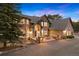 Beautiful exterior evening view of the home showing the front facade, a stone entryway, and manicured landscaping at 30205 Telluride Ln, Evergreen, CO 80439