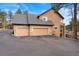 Side exterior view of the home showing three garage doors and asphalt driveway at 30205 Telluride Ln, Evergreen, CO 80439