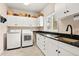 Well-organized laundry room features white cabinets, dark countertops, appliances, and natural light at 30205 Telluride Ln, Evergreen, CO 80439