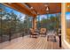 A relaxing outdoor seating area on a deck with wood flooring and covered ceiling, looking out to the trees at 30205 Telluride Ln, Evergreen, CO 80439