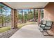 Outdoor patio with stone pillar supports and a view of the forest, plus comfortable green metal chairs at 30205 Telluride Ln, Evergreen, CO 80439