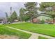 Charming home with a lush green lawn, mature trees, and inviting front porch at 3355 S Flower St # 166, Lakewood, CO 80227