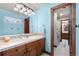 Bright bathroom featuring tiled counters, wood cabinets, and a framed doorway to the shower and toilet area at 5159 Serene View Way, Parker, CO 80134