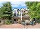 Exterior elevation featuring a stone patio, covered deck with hot tub and lush green trees at 5159 Serene View Way, Parker, CO 80134