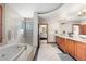 A bright primary bathroom with double sinks, custom wood cabinets, travertine tile flooring and large soaking tub at 5159 Serene View Way, Parker, CO 80134