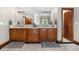 Beautiful primary bathroom with double sinks, custom wood cabinets, and travertine tile flooring at 5159 Serene View Way, Parker, CO 80134