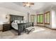 A bright primary bedroom featuring a tray ceiling, plush carpet, and large windows with wooded shutters at 5159 Serene View Way, Parker, CO 80134