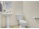 Bathroom with pedestal sink, modern toilet, and round mirror in neutral tones at 1518 Whitehall Dr, Longmont, CO 80504