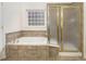 Tiled bathroom featuring a soaking tub, glass shower, and a privacy window at 1518 Whitehall Dr, Longmont, CO 80504