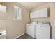 Practical laundry room with washer, dryer, and overhead cabinets for storage at 5010 Apache Creek Rd, Castle Rock, CO 80109
