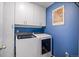 A well-lit laundry room boasts a side-by-side washer and dryer with overhead cabinet storage at 26304 E 4Th Pl, Aurora, CO 80018