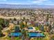 Aerial view of a community featuring blue tennis courts, a pool, mature trees, and mountain views at 6997 S Poplar Way, Centennial, CO 80112