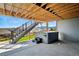 Covered patio featuring a luxurious hot tub beneath a staircase, blending indoor comfort with outdoor views at 18212 W 95Th Pl, Arvada, CO 80007