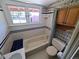 Functional bathroom featuring a tiled tub, wooden cabinet storage, and a bright window at 2902 Depew St, Wheat Ridge, CO 80214